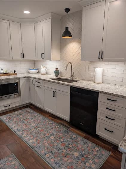 Finished sink wall with herringbone accent, white cabinetry, and black fixtures