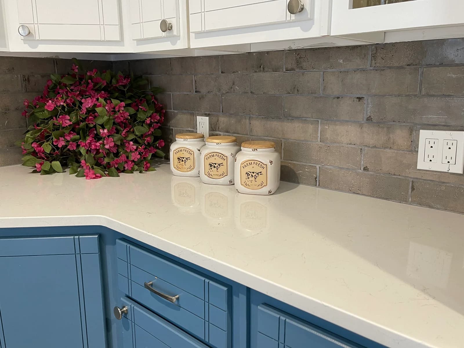 Detail of the blue cabinetry, quartz surface, and tiled backsplash